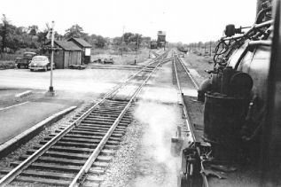 The photo shows the engineer’s view of the grade crossing at Tichborne, where the steam engine has turned west onto the main CPR line to pick up coal at the coaling tower, visible in the background (The picture was taken by David Page in 1956.)